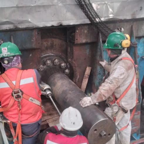 Cuadrilla con equipo de protección trabajando en un eje dentro de una planta