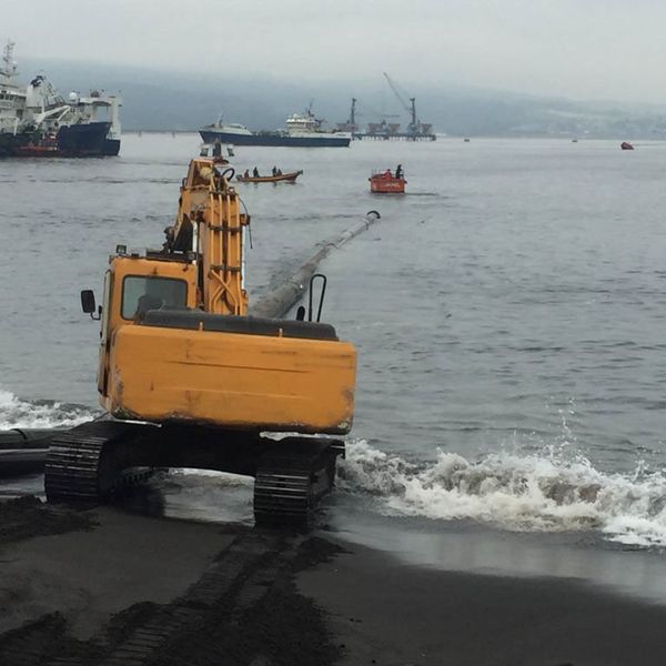 Excavadora en el mar lanzando una tubería