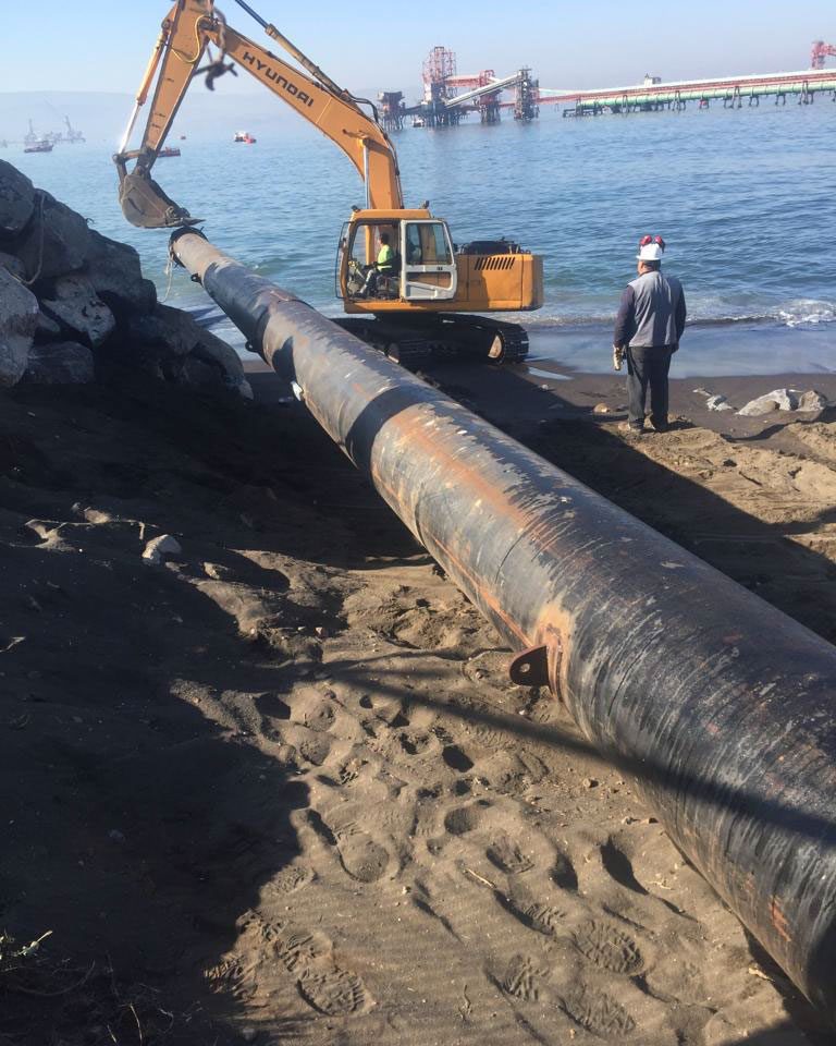 Tubería en la playa junto a una excavadora durante el lanzamiento