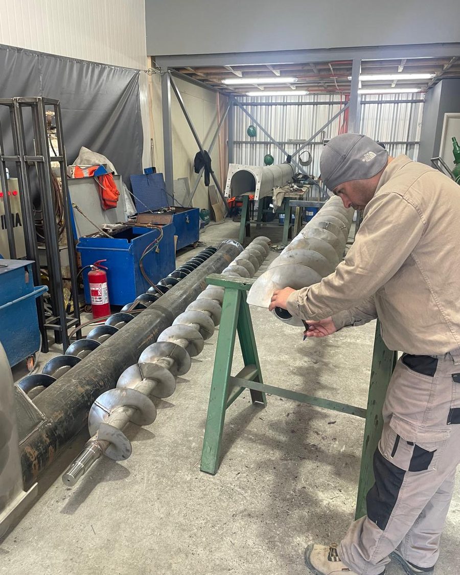 Trabajador revisando un tornillo helicoidal en el taller